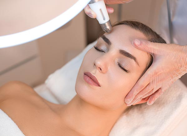 A woman with her eyes closed receiving a facial skin treatment in a clinic